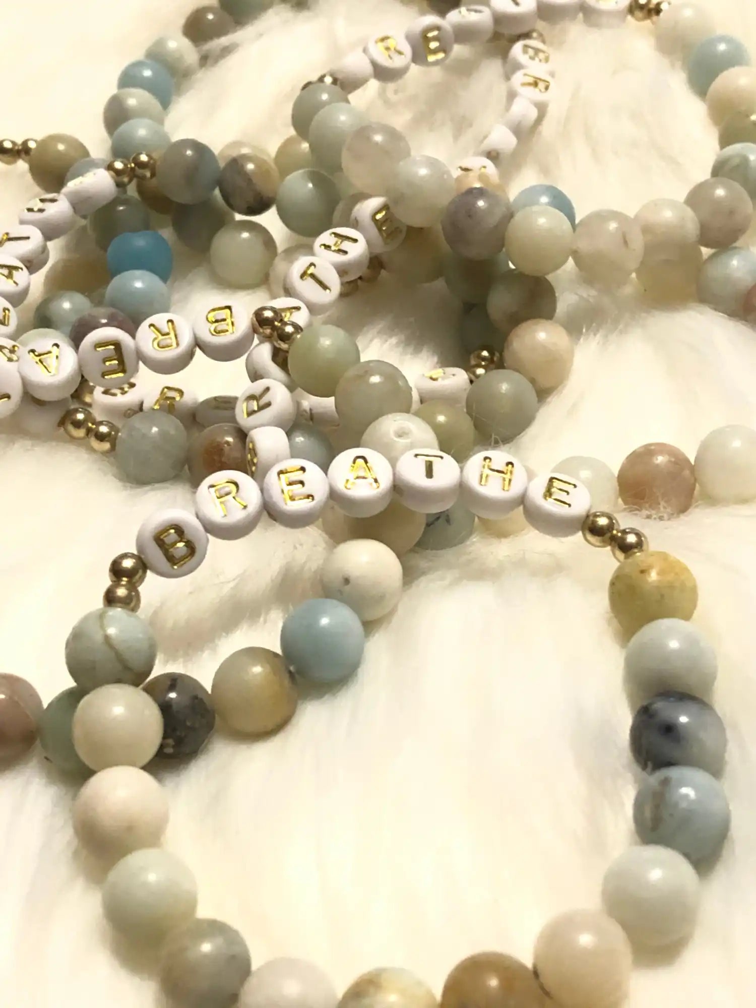 Multiple beaded bracelets with lettered beads.